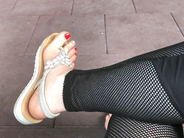Sandalen necken im Freien mit roten Zehennägeln und Zehen wackeln