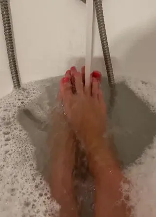 Füße im Schaum im Wasserstrahl plätschern