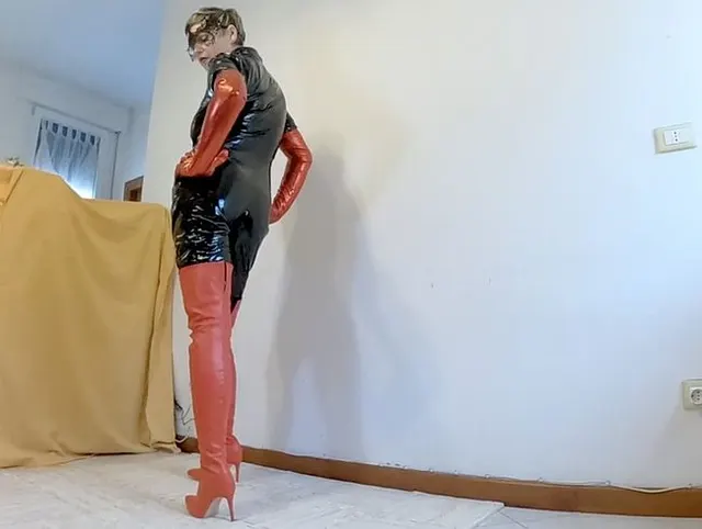 Catsuit mit langen roten Stiefeln und roten Handschuhen posiert