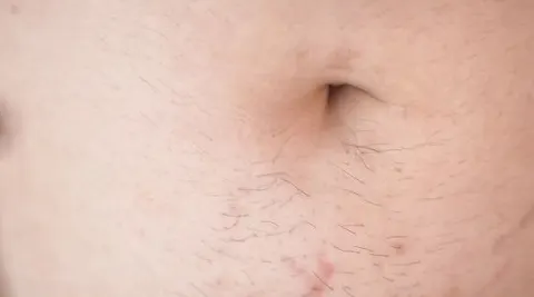 behaarter Bauch und Bauchnabel mit Sperma