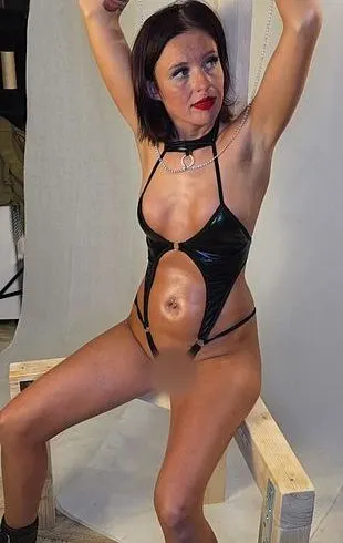 Kristy im knappen schwarzen Leder Body auf dem Kitzelstuhl