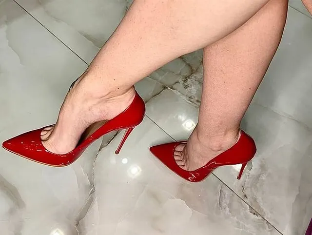 Sie baumelte mit roten High Heels ohne die Hilfe ihrer Hände