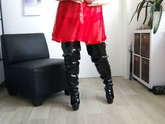 In rotem Dessous mit schwarzen Lackstiefeln und dicken Eutern