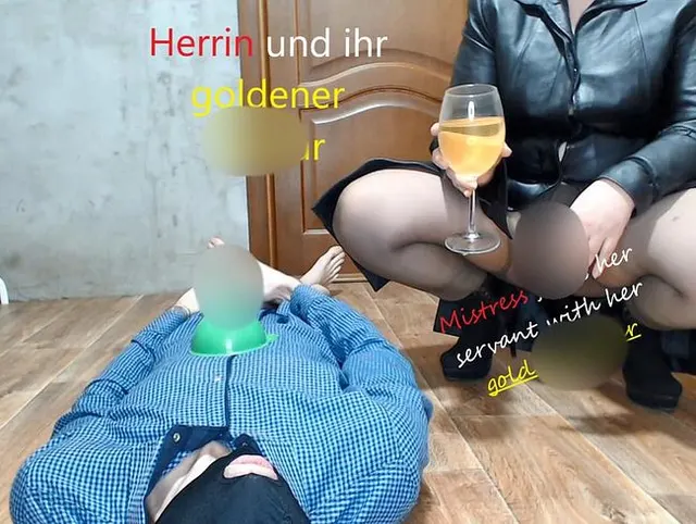 Herrin in einer Lederjacke füttert ihren Diener mit ihrem goldenen Nektar